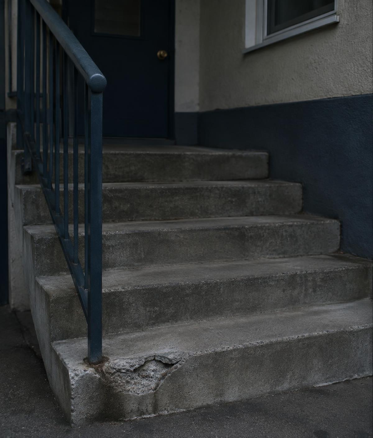 Exterior concrete stairway with a broken, crumbling bottom step